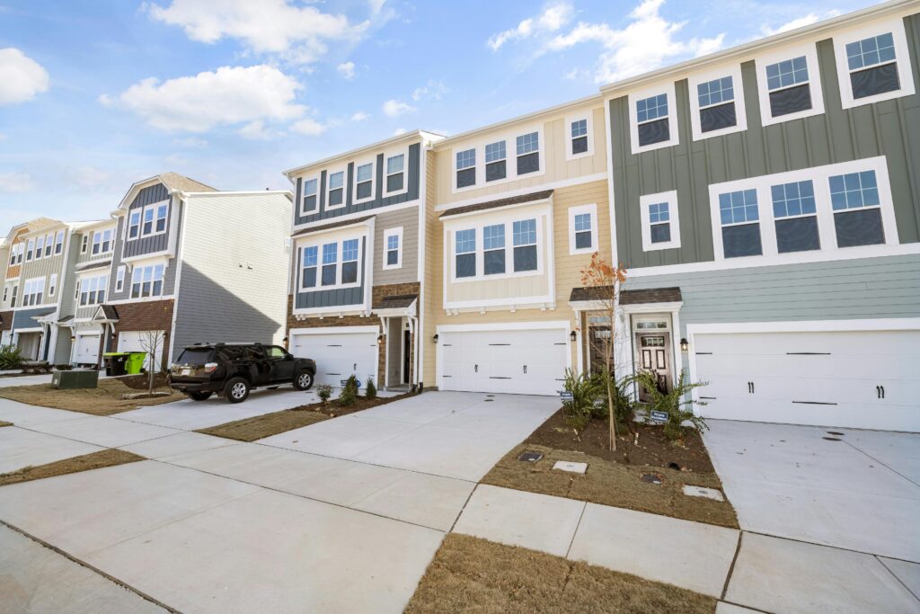 A row of colorful modern townhouses in a suburban neighborhood on a sunny day.